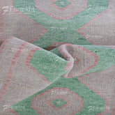 Close-up of a patterned fabric with geometric design, featuring green and red colors.
