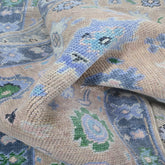 Close-up of a patterned rug with blue, green, and beige colors.