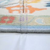 Colorful rug with a ruler for scale, featuring the brand &