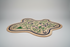 Irregular shaped hand-tufted rug with green floral and geometric patterns on a beige base.